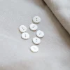 boutons coquillage posés sur un tissu en lin