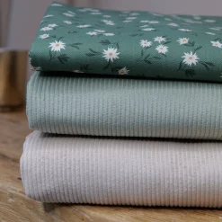 pile de tissus en coton, velours côtelé écru, velours côtelé vert sauge et twill de coton fleurs blanches sur fond vert